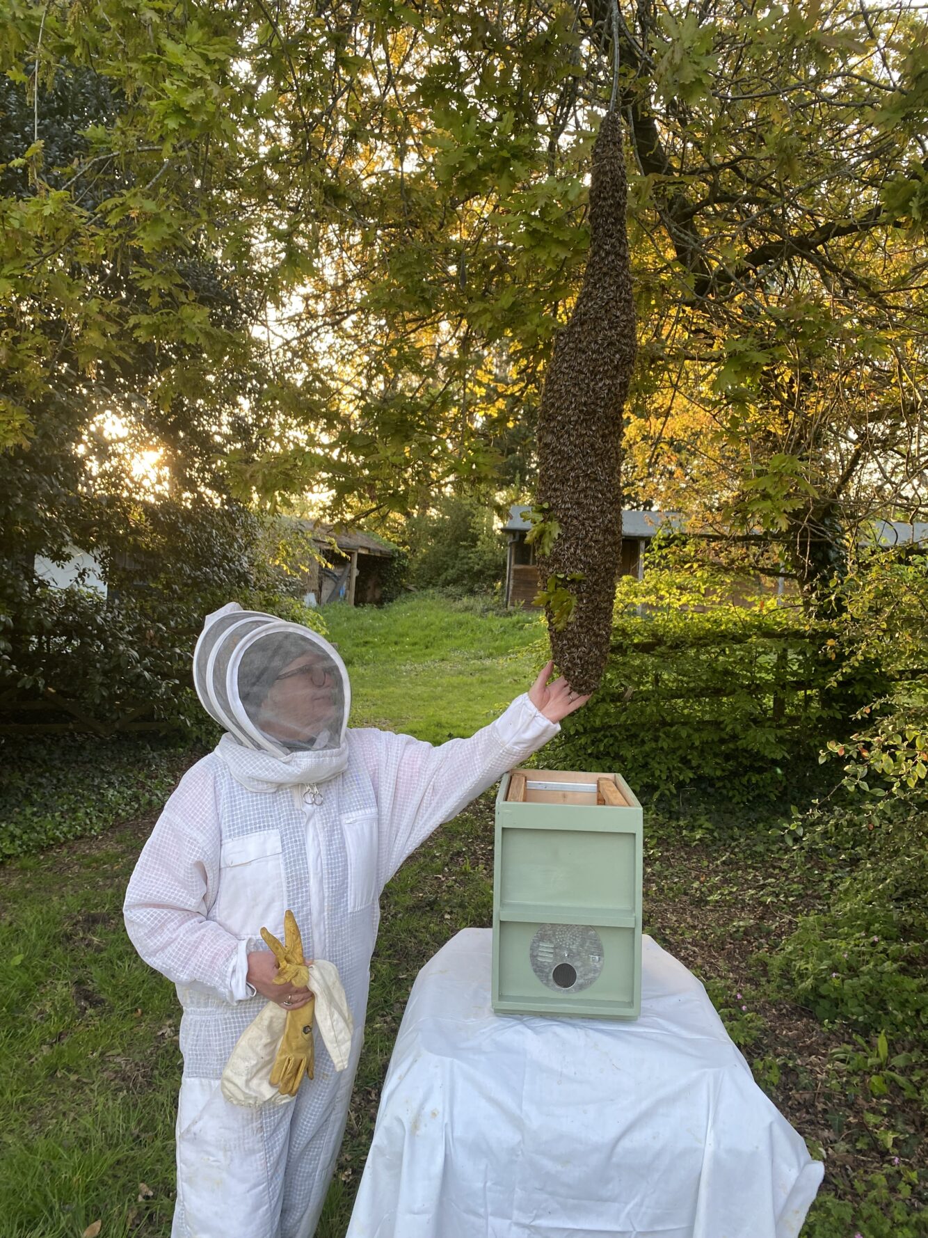 Image of Ruth in protective gear next to one of the beehives